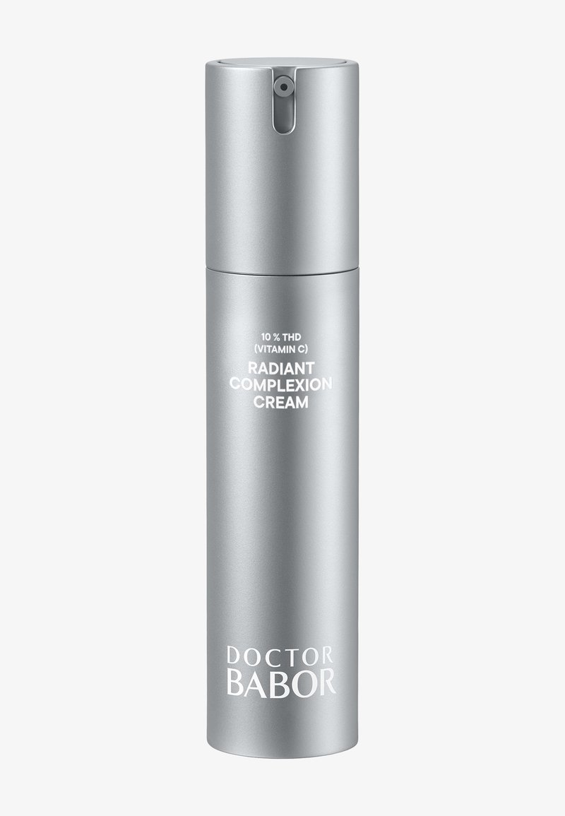Flacon pompe argenté étiqueté "Crème éclatante 10 % THD (Vitamine C)" par Doctor Babor sur un fond clair et uni.