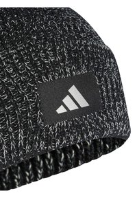 Gorro tricotado em preto e branco com um padrão texturizado; apresenta um retângulo preto com um logótipo branco exibindo três riscas diagonais.