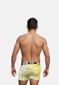 Boxer shorts jaunes avec un motif graphique comprenant divers gribouillis et icônes, dotés d'une ceinture élastique noire avec le texte "MR LO".