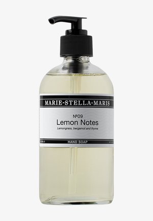 Bouteille en verre transparente avec une pompe noire, étiquetée "Lemon Notes", dotée d'un design noir et blanc ; contient un savon liquide transparent.