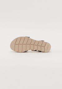 Brown sandal with a light tan rubber sole; features textured grip patterns and a logo. Adjustable straps for fit.