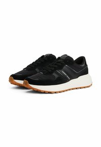 Zapatillas de running negras hechas de ante y materiales sintéticos, con una gruesa entresuela blanca y una suela de goma con un patrón texturizado.