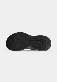 Черна гумена подметка с релефен грайфер и име на марката "saucony" в зоната на свода, показана от долната страна на сив фон.