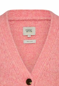 Różowy kardigan z wełny z dekoltem w serek, z pojedynczym brązowym guzikiem i teksturowanym wzorem dzianiny. Etykiety widoczne w środku.