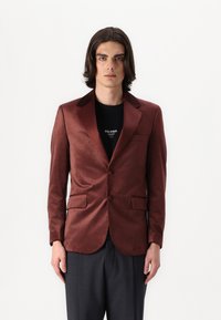 Blazer burdeos con un acabado satinado, solapas con muesca, dos bolsillos frontales y un cierre de un solo botón, superpuesto sobre una camisa negra.