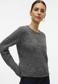 Pull en tricot gris avec un col rond, des manches longues et un ourlet côtelé. Confectionné en fil doux et texturé, offrant une coupe décontractée.