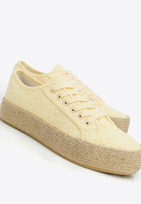 Gelbe Leinensneaker mit floralem Muster, beige geflochtener Plattformsohle und passenden Schnürsenkeln. Runde Zehenpartie und Low-Top-Design.