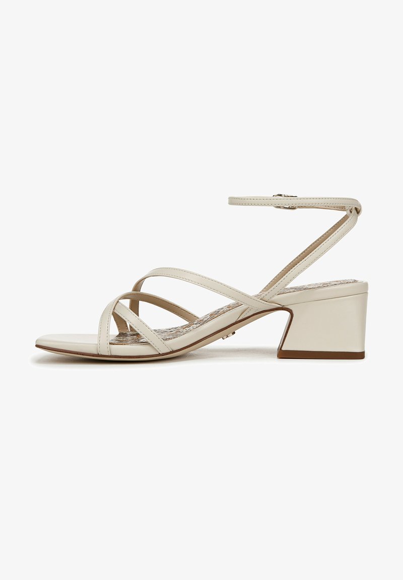 Beige hakken sandalen met gekruiste banden, open teen en een blokhak. Rijke textuur en subtiele patroonvoering. Verstelbare enkelband.