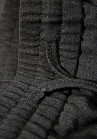 Zwarte textuurlijk stof met een geribbeld patroon en zichtbare stikdetails, met plooien en lussen voor aanpassing.