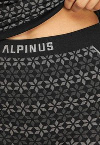 Czarne legginsy termiczne z teksturowanym, floralnym wzorem w odcieniu szarości oraz czarnym pasem wytłoczonym nazwą "ALPINUS".