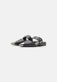 Musta nahkainen slingback-kengät, joissa on terävä kärki, hopeiset metallikoristeet ja leveät nauhat, joissa on solki. Littee design.