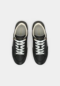 Μαύρα αθλητικά παπούτσια από συνθετικό δέρμα, με λευκά κορδόνια, λευκή σόλα και χρυσές λεπτομέρειες της μάρκας στη γλώσσα και το πλάι.