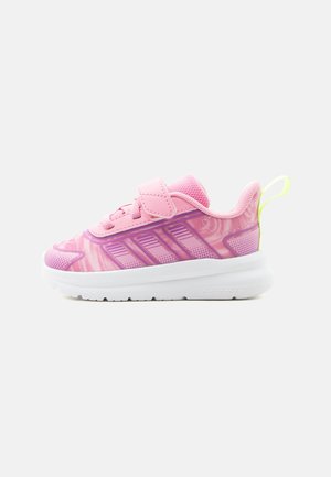 Pantof sport roz pentru copii cu accente mov, talpă albă, o singură bandă Velcro, limba din plasă și maner galben la călcâi, vedere laterală.