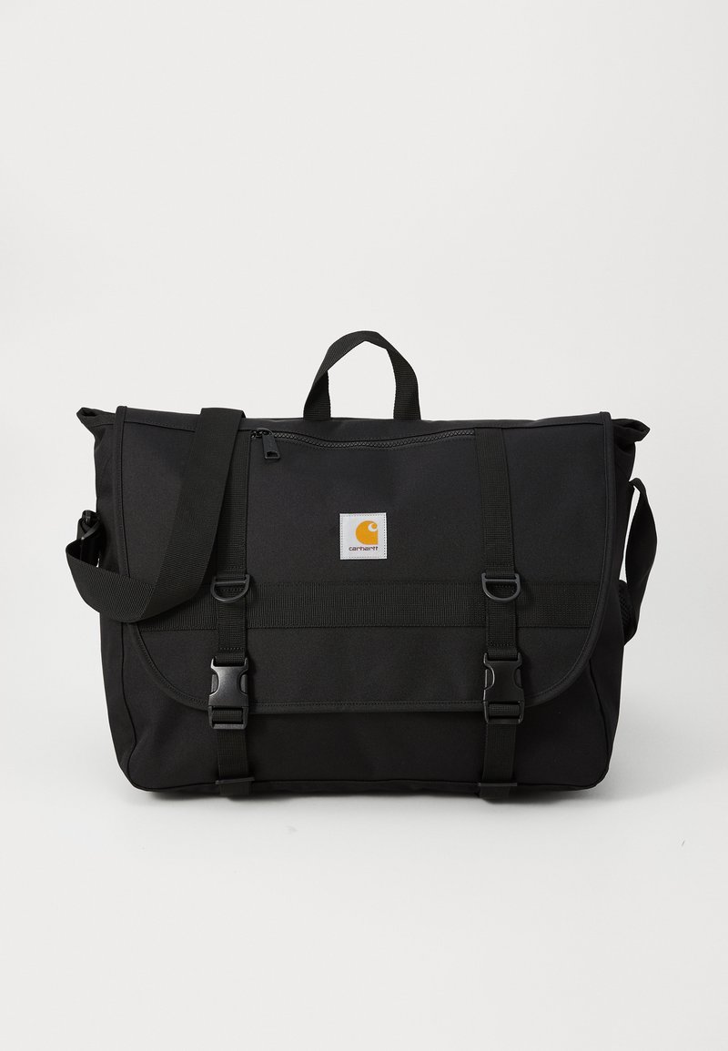 Sac messager noir en tissu durable, doté d'une fermeture à rabat, d'une bandoulière réglable et d'une patch logo à l'avant avec des accents en métal.
