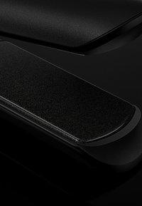 Deux appareils électroniques noirs élégants avec des surfaces texturées, placés sur une surface noire réfléchissante, présentant des bords lisses et arrondis.