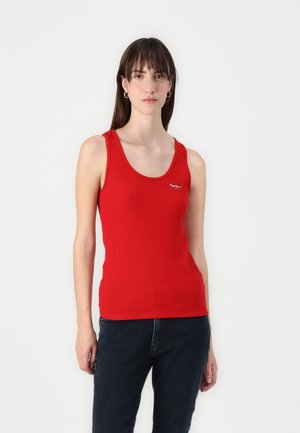 Rød ribbestrikket tanktop med rund hals, med en liten logo på brystet, sammen med mørke jeans. Glatt tekstur og tettsittende design.
