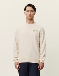 Beige pulóver 100% pamutból, kerek nyakkal és hosszú ujjakkal. Zöld "LES DEUX" felirat a mellkasán. Bordás mandzsetták és alsó szegély.