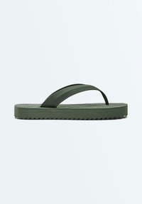 Tongs en caoutchouc vert avec semelle texturée et large bride, vues de côté sur un fond clair uni.