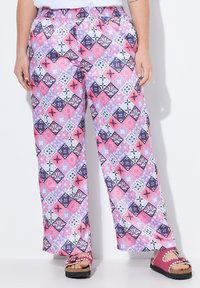 Gemusterte weite Hosen mit einem mehrfarbigen Diamantdesign in Pink, Lila und Schwarz. Elastischer Bund für zusätzlichen Komfort. Ergänzt durch eine pinke Sandale.