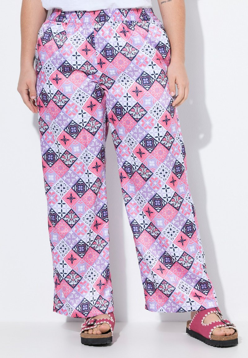 Gemusterte weite Hosen mit einem mehrfarbigen Diamantdesign in Pink, Lila und Schwarz. Elastischer Bund für zusätzlichen Komfort. Ergänzt durch eine pinke Sandale.