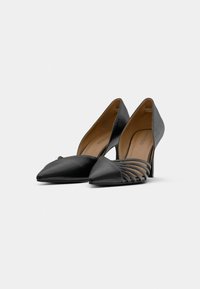 Pantofi negri cu toc înalt, având vârf ascuțit și design decupat. Realizați din piele netedă și texturată, cu un toc stiletto elegant.