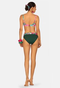 Zestaw bikini z kwiatowym wzorem na górze i jednolitym, ciemnozielonym dołem. Teksturowana tkanina z regulowanymi ramiączkami oraz pasującą gumką do włosów.