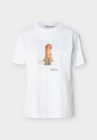 Λευκό μπλουζάκι με μια κεντρική εκτύπωση ενός καφέ σκύλου που κάθεται πίσω από δύο πράσινες μπότες και το κείμενο "BARBOUR" από κάτω.