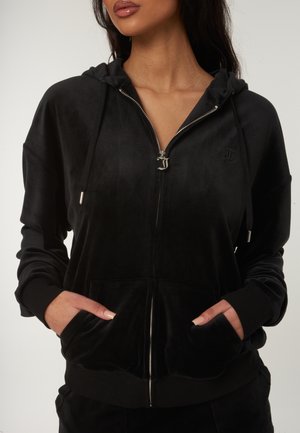 Zwarte hoodie met ritssluiting, gemaakt van zacht, fluweelachtig materiaal, met een capuchon, voorzakken en zilveren ritsdetails; voorzien van een subtiel logo op de borst.