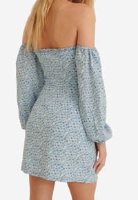 Mini-robe fleurie bleue avec manches bouffantes, dotée d'un corsage ajusté, d'un col élastique et d'un tissu léger et texturé.