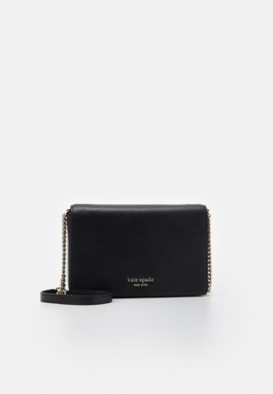 Sac bandoulière en cuir noir avec une lanière chaîne dorée et le logo "kate spade new york" en centre avant sur fond blanc.