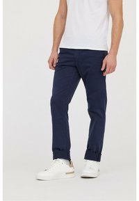 Chinos bleu marine avec une coupe ajustée. Fabriqués en tissu léger, avec des ourlets retournés et des poches latérales. Associés à des baskets blanches.