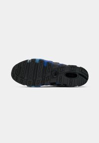 Black and blue athletic shoe sole with textured tread pattern and circular logo near the arch on a white background.