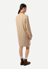 Robe-pull beige à manches longues et coupe décontractée, confectionnée dans un tissu doux. Détails notables : encolure ronde et ourlet côtelé.