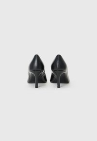 Scarpe nere in pelle con tacco alto, punta affusolata e sottile tacco a stiletto. Texture liscia con dettagli di cucitura delicati sul retro.