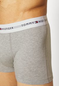 Sivi pamučni bokserice s bijelim elastičnim pojasom na kojem je natpis "TOMMY HILFIGER". Prilagođen dizajn s glatkom teksturom.