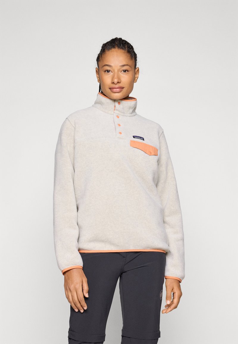 Pullover in pile grigio chiaro con colletto alto, dettagli arancioni sulla tasca e sull'orlo, bottoni sul davanti e un patch con il logo.