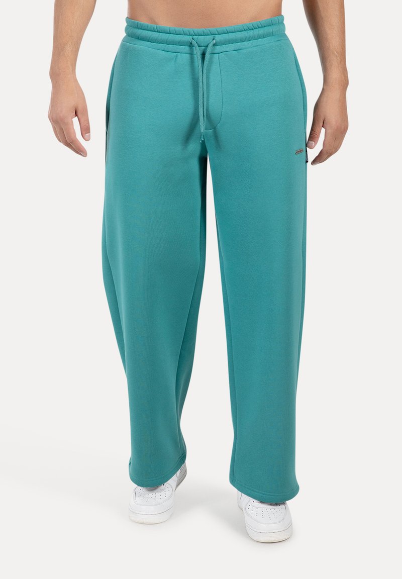 Turkusowe spodnie dresowe o luźnym kroju, z elastycznym pasem, bocznymi kieszeniami i subtelnym logo. Miękka tkanina o gładkiej fakturze.
