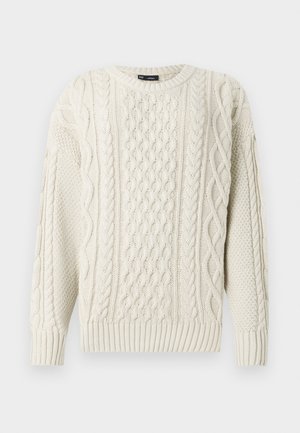 Krēmveida adīts džemperis ar kabeli rakstiem un ribotām piedurknēm. Klasiska apaļā kakla izgriezums ar teksturētu apdari. Redzami nav nekādu metāla detaļu.