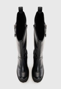 Fekete bőr, térd fölé érő csizmák sima textúrával, oldalsó cipzárral és hurkos húzófülekkel a tetején. Lapos talp és diszkrét varrási részletek.