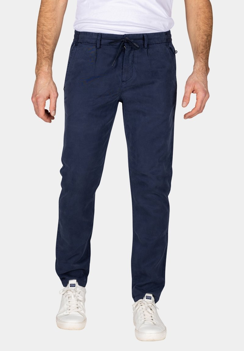 Navyblauwe katoenen broek met een trekkoord in de taille, rechte pijpen en zijzakken. Gecombineerd met witte sneakers voor een casual look.