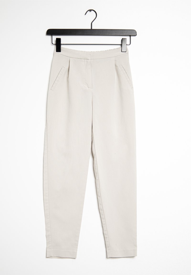 Pantalon beige à jambes droites avec poches avant accroché sur un cintre noir sur fond blanc.