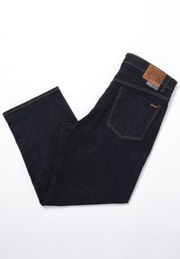 Ciemne jeansy z denimu o zwężanej nogawce; posiadają brązową skórzaną naszywkę, kontrastowe szwy oraz standardowe tylne kieszenie.
