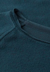 Türkise Wollmischung mit weicher Textur und geripptem Kragen. Verfügt über eine gestickte Kantendetailierung und eine leichte Melierung.