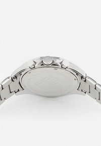 Montre en acier inoxydable argenté avec un boîtier arrondi lisse, trois boutons et un bracelet à maillons. Logo de la marque gravé au dos.