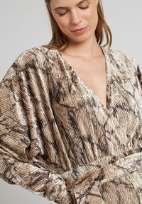 Vestido envolvente a rayas marrón y crema en un suave tejido texturizado con un escote en V pronunciado y mangas largas. Incluye un cinturón en la cintura.