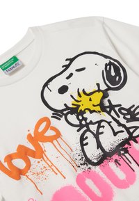 Bílá bavlněná mikina s černým obrysem psa, žlutými detaily a barevným graffiti stylem napsaným "láska" v oranžové a růžové barvě.