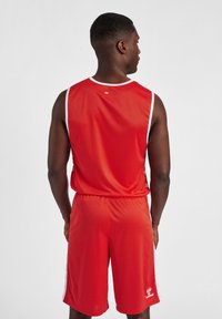 Rød atletisk tanktop og shorts sæt, lavet af glat, let materiale. Har hvide accenter og et lille logo på shortsene.