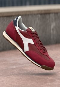 Red athletic shoe with a suede and mesh upper, white accent detailing, lace closure, and a gum rubber outsole.