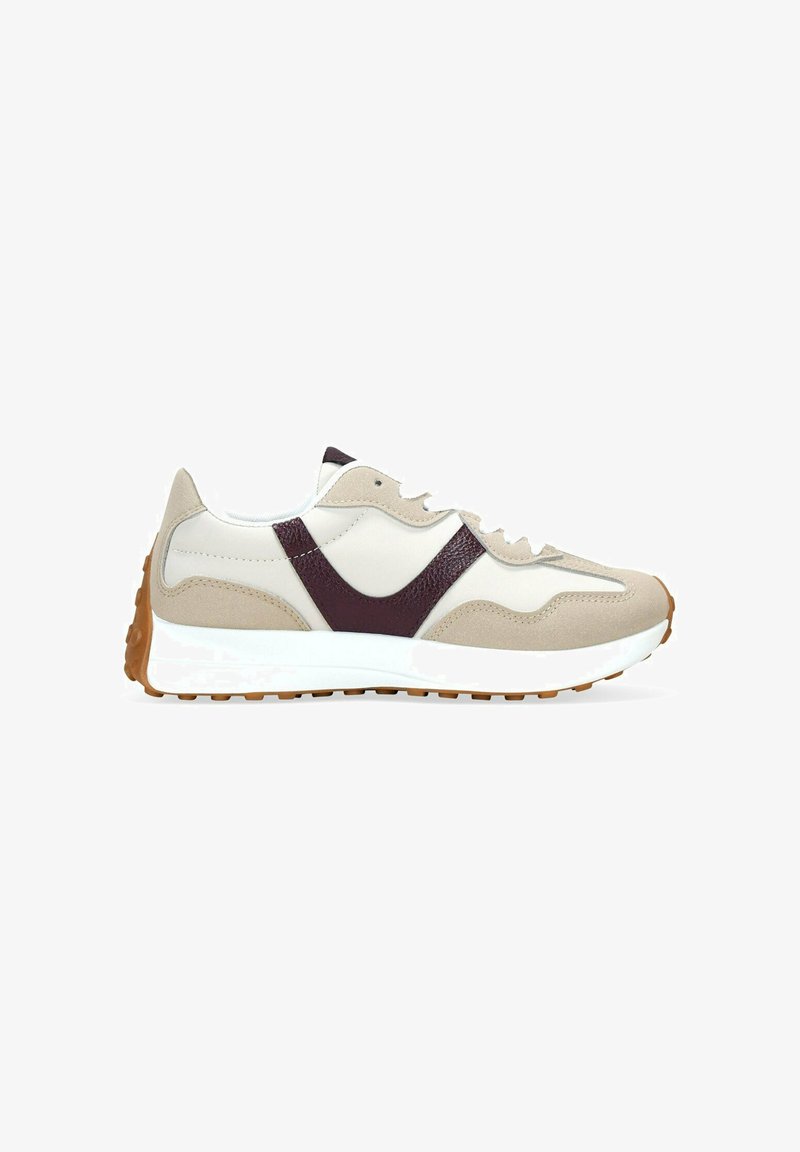 Zapatilla beige y blanca con acentos de cuero color marrón, suela blanca y suela de goma, mostrada de lado sobre un fondo blanco.