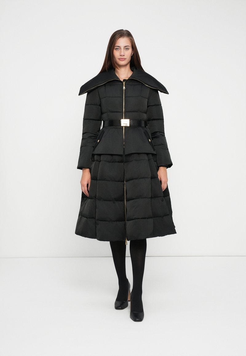 Black puffer coat with a high collar, gold zipper, and belt. Features a knee-length skirt with a pleated design and side pockets.
